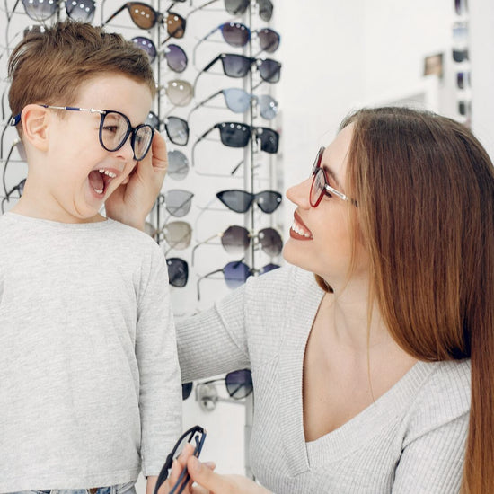 Boy and woman trying on eyeglasses together at optical shop.