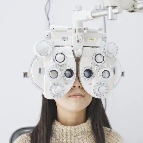 Woman seated behind phoropter for an eye examination